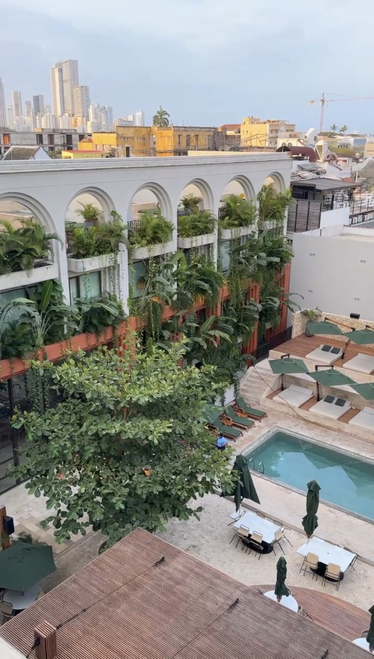 Lush boutique hotel with arched balconies and a rooftop pool
